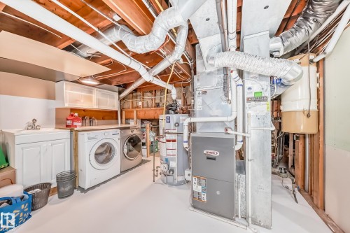 Utility area featuring a washer and dryer, a sink, and exposed wooden ceiling beams - 3107 43 Avenue, Edmonton, AB - Indoor Photo Showing Laundry Room
