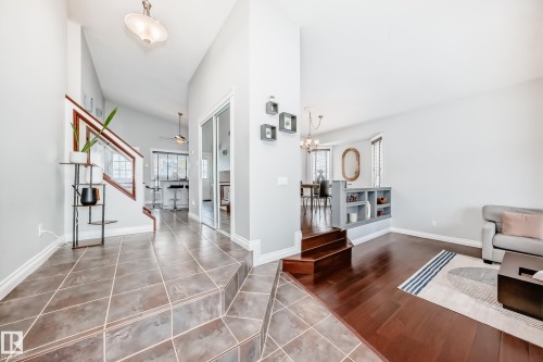 Entryway and living area featuring tiled flooring, hardwood flooring, a staircase with a wooden handrail, and built-in shelving - 3107 43 Avenue, Edmonton, AB - Indoor