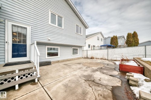 The property features a concrete patio area, a white chain link fence, and a raised garden bed - 3107 43 Avenue, Edmonton, AB - Outdoor