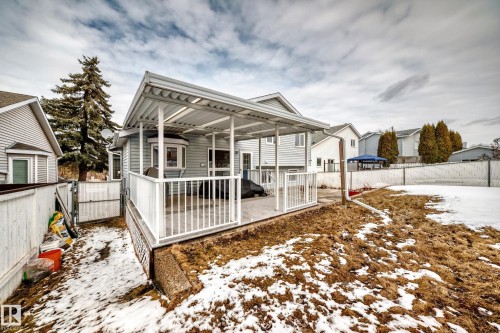 The property features a covered back deck with white railings, a fenced yard, and a bay window - 3107 43 Avenue, Edmonton, AB - Outdoor With Deck Patio Veranda