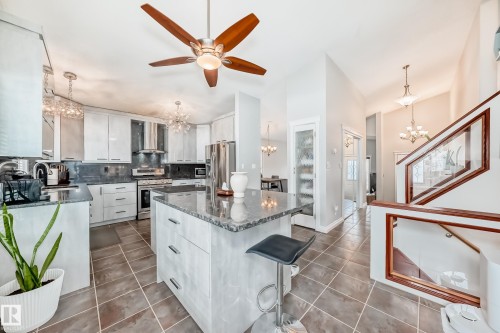 Kitchen and living area featuring high ceilings, a ceiling fan with wooden blades, light gray cabinetry, and dark tiled flooring - 3107 43 Avenue, Edmonton, AB - Indoor Photo Showing Kitchen With Upgraded Kitchen