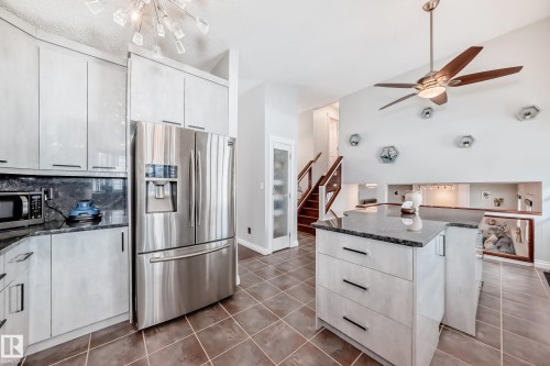 The kitchen features a stainless steel refrigerator, a microwave, and ample cabinetry - 3107 43 Avenue, Edmonton, AB - Indoor Photo Showing Kitchen With Stainless Steel Kitchen