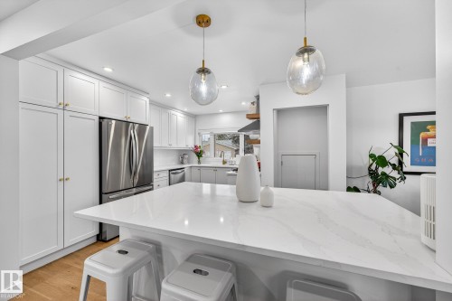Kitchen with a kitchen bar, stainless steel appliances, white cabinets, light wood-style floors, and pendant lighting - 8604 142 Street, Edmonton, AB - Indoor Photo Showing Kitchen With Upgraded Kitchen
