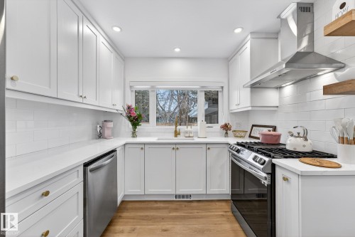 Kitchen featuring stainless steel appliances, light stone counters, white cabinets, light wood-style flooring, and recessed lighting - 8604 142 Street, Edmonton, AB - Indoor Photo Showing Kitchen With Stainless Steel Kitchen With Upgraded Kitchen