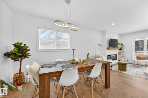 Dining area with a glass covered fireplace, light wood finished floors, and recessed lighting - 8604 142 Street, Edmonton, AB - Indoor Photo Showing Dining Room With Fireplace