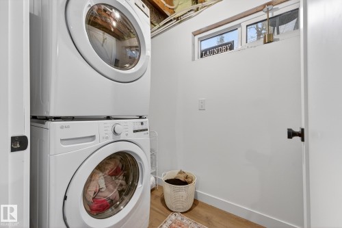 Laundry area featuring stacked washer / dryer and light wood-style flooring - 8604 142 Street, Edmonton, AB - Indoor Photo Showing Laundry Room