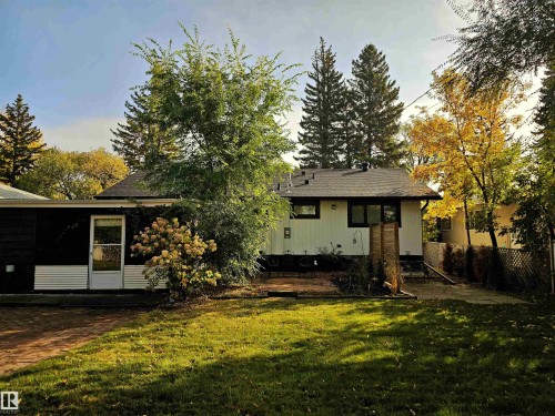 The property features an extensive lawn area, a paved patio, and mature trees - 8604 142 Street, Edmonton, AB - Outdoor