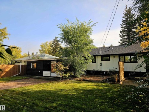 The property features a spacious yard with a lawn, mature trees, and a paved patio area - 8604 142 Street, Edmonton, AB - Outdoor