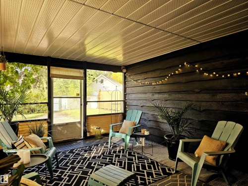 The screened-in porch offers a comfortable outdoor living space with a black and white patterned rug, a dark wood wall with string lights, and a light-colored ceiling - 8604 142 Street, Edmonton, AB -  With Exterior