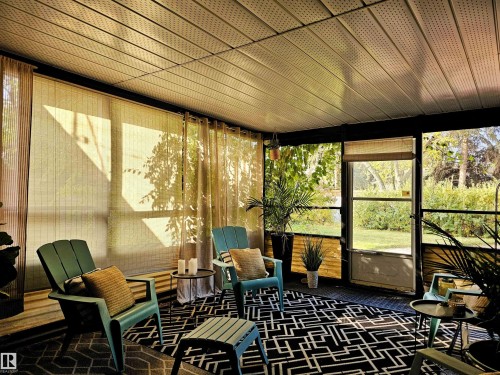 Enclosed patio space with a screened door and windows, featuring a geometric patterned rug and a paneled ceiling - 8604 142 Street, Edmonton, AB -  With Exterior
