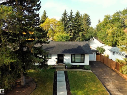 The property features a white exterior with a black roof, dark-framed windows, and a black front door, complemented by a concrete walkway leading to the entrance - 8604 142 Street, Edmonton, AB - Outdoor
