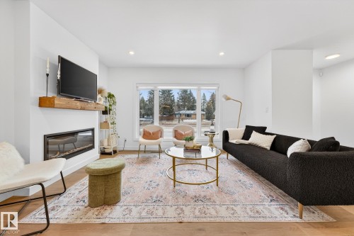 Living area featuring light wood-style flooring, a glass covered fireplace, and recessed lighting - 8604 142 Street, Edmonton, AB - Indoor Photo Showing Living Room With Fireplace