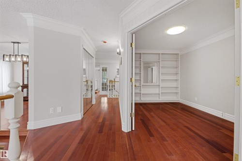 Hardwood flooring extends throughout this well-lit space, featuring crown molding, baseboards, and a room with built-in shelving - 131 Walsh Crescent, Edmonton, AB - Indoor Photo Showing Other Room