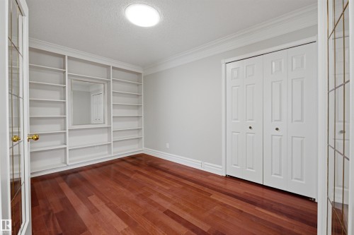 This room features rich hardwood flooring, built-in shelving, and white bi-fold closet doors - 131 Walsh Crescent, Edmonton, AB - Indoor Photo Showing Other Room