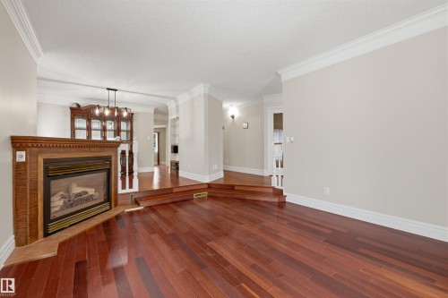 Living area featuring hardwood flooring, a fireplace with a wood surround, and crown molding - 131 Walsh Crescent, Edmonton, AB - Indoor Photo Showing Living Room With Fireplace