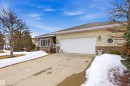 This property features a light-colored brick exterior with stone accents, a two-car garage with a white door, and a concrete driveway - 131 Walsh Crescent, Edmonton, AB  - Outdoor 