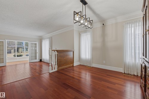 Spacious interior featuring hardwood flooring, crown molding, and a modern rectangular chandelier - 131 Walsh Crescent, Edmonton, AB - Indoor