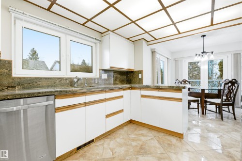 The kitchen features white cabinetry with wood trim, granite countertops, and a stainless steel dishwasher - 131 Walsh Crescent, Edmonton, AB - Indoor Photo Showing Kitchen