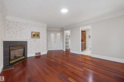 Living space featuring rich hardwood flooring, a fireplace with a black tile surround, and crown molding - 131 Walsh Crescent, Edmonton, AB - Indoor Photo Showing Living Room With Fireplace