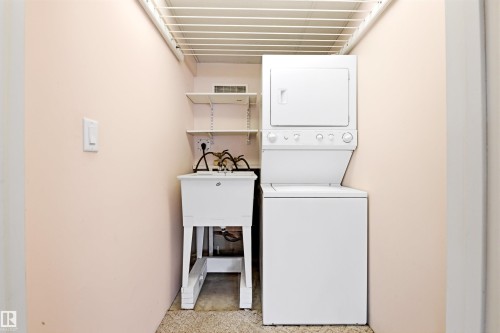 Dedicated laundry area featuring a stackable washer and dryer, a utility sink, and wall-mounted shelving - 131 Walsh Crescent, Edmonton, AB - Indoor Photo Showing Laundry Room