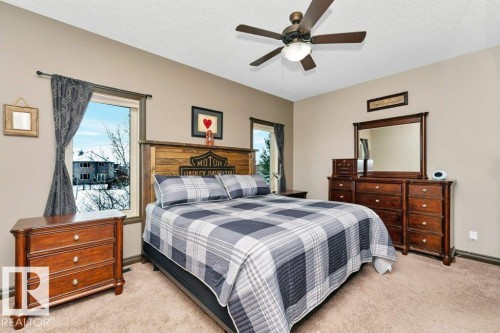 This bedroom features neutral-toned walls, windows with dark trim, and a ceiling fan with integrated lighting - 33 Hillcrest Point(E), Fort Saskatchewan, AB - Indoor Photo Showing Bedroom
