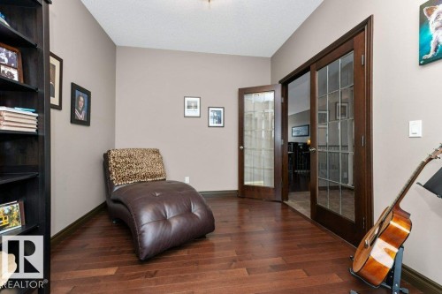 This room features rich hardwood flooring, neutral wall paint, and a corner bookshelf - 33 Hillcrest Point(E), Fort Saskatchewan, AB - Indoor