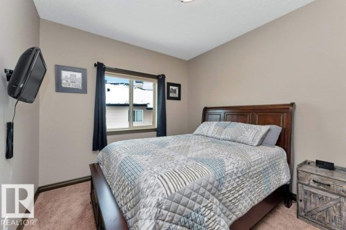 This bedroom features a dark wood bed frame, neutral-toned walls, and a window with dark curtains - 33 Hillcrest Point(E), Fort Saskatchewan, AB - Indoor Photo Showing Bedroom