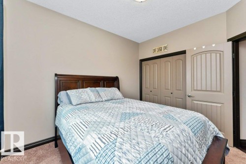 This bedroom features soft beige walls, a dark wood bed frame, and soft brown carpeting - 33 Hillcrest Point(E), Fort Saskatchewan, AB - Indoor Photo Showing Bedroom