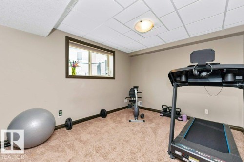 This versatile room features neutral-toned walls, carpeted flooring, and a drop ceiling with recessed lighting - 33 Hillcrest Point(E), Fort Saskatchewan, AB - Indoor Photo Showing Gym Room