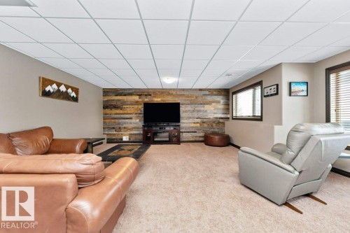 The property features a spacious room with light-colored carpeted floors and a drop ceiling - 33 Hillcrest Point(E), Fort Saskatchewan, AB - Indoor