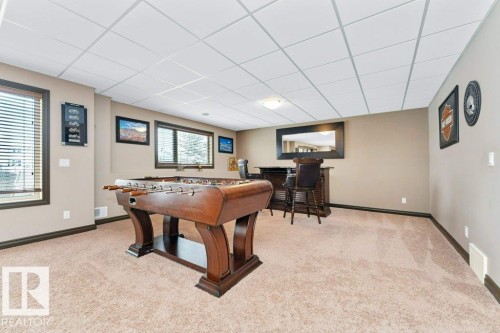 This spacious room features neutral-toned carpet, light beige walls, and white ceiling tiles - 33 Hillcrest Point(E), Fort Saskatchewan, AB - Indoor Photo Showing Other Room