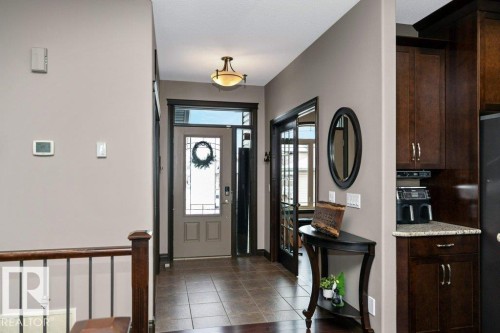 The property features a welcoming entryway with tiled flooring and a dark wood front door, framed by a transom and sidelights - 33 Hillcrest Point(E), Fort Saskatchewan, AB - Indoor Photo Showing Other Room
