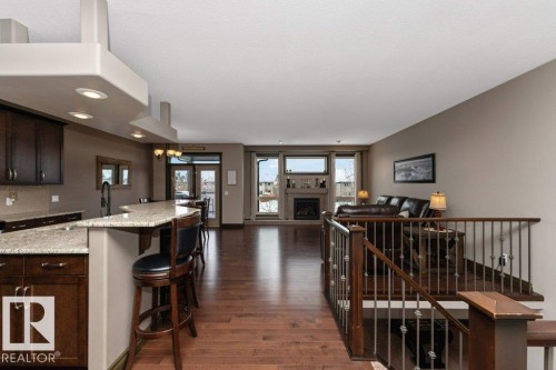 Open concept living space featuring hardwood floors, a kitchen island with seating, and a living area with a fireplace - 33 Hillcrest Point(E), Fort Saskatchewan, AB - Indoor