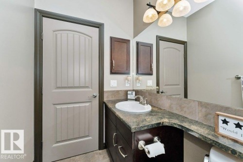 The bathroom features a vanity with a counter and an integrated sink, illuminated by a light fixture with multiple shades - 33 Hillcrest Point(E), Fort Saskatchewan, AB - Indoor Photo Showing Bathroom