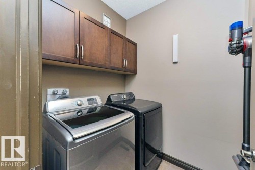 The property includes a dedicated laundry area with overhead brown cabinetry and a light-colored wall - 33 Hillcrest Point(E), Fort Saskatchewan, AB - Indoor Photo Showing Laundry Room