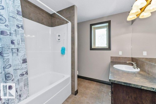 Bathroom featuring a tub and shower combination with a shower curtain, a vanity with an integrated sink, and a framed window - 33 Hillcrest Point(E), Fort Saskatchewan, AB - Indoor Photo Showing Bathroom