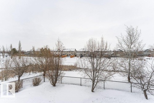 The property features an extensive backyard with a chain-link fence, mature trees, and a snow-covered landscape - 33 Hillcrest Point(E), Fort Saskatchewan, AB - Outdoor