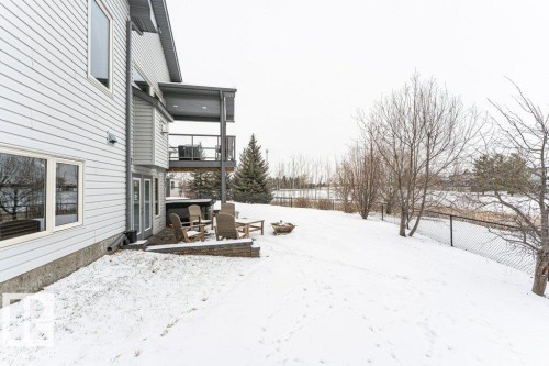 The property features a two-story exterior with light-colored siding and a balcony overlooking a spacious yard - 33 Hillcrest Point(E), Fort Saskatchewan, AB - Outdoor