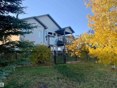 The property features light-colored siding, a dark roof, and an elevated outdoor living space with a dark railing - 33 Hillcrest Point(E), Fort Saskatchewan, AB - Outdoor