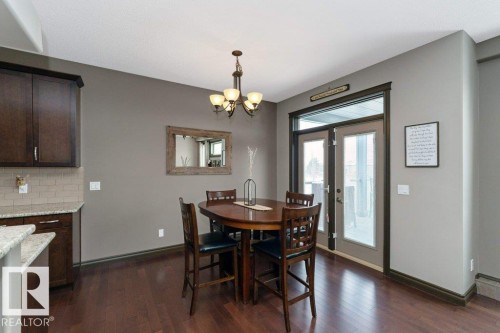 Dining area featuring hardwood floors, a chandelier, and double doors providing access to the outside - 33 Hillcrest Point(E), Fort Saskatchewan, AB - Indoor Photo Showing Dining Room
