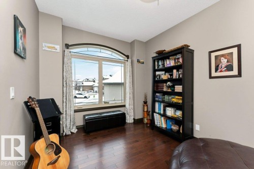 This room features hardwood flooring, a large window with an arched transom, and neutral-toned walls - 33 Hillcrest Point(E), Fort Saskatchewan, AB - Indoor