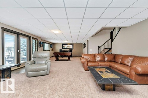 Spacious room featuring carpeted flooring, a panel ceiling, and double glass doors providing outdoor access - 33 Hillcrest Point(E), Fort Saskatchewan, AB - Indoor