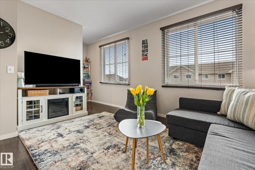 Living area featuring dark flooring, light-colored walls, and windows with blinds providing natural light - 165 603 Watt Boulevard, Edmonton, AB - Indoor Photo Showing Living Room