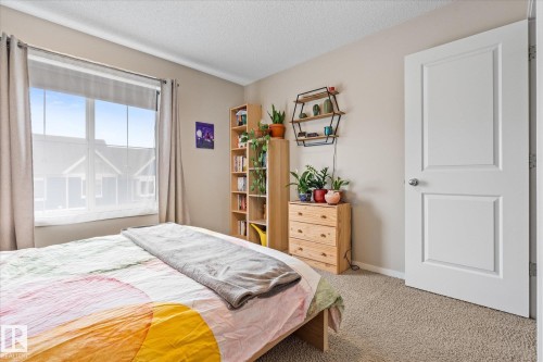 The bedroom features a large window with natural light, a neutral color palette, and carpeted flooring - 165 603 Watt Boulevard, Edmonton, AB - Indoor Photo Showing Bedroom