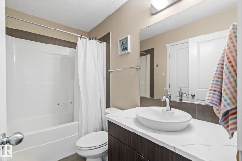 The bathroom features a vessel sink, a white countertop, and a shower-tub combination with a white shower curtain - 165 603 Watt Boulevard, Edmonton, AB - Indoor Photo Showing Bathroom