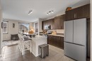 The kitchen features dark wood cabinetry, a stainless steel refrigerator, and track lighting - 165 603 Watt Boulevard, Edmonton, AB  - Indoor Photo Showing Kitchen 