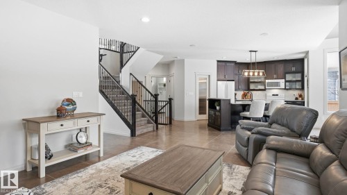 The open concept living area features a kitchen with dark cabinetry, a central island with seating, and a modern light fixture - 131 North Ridge Drive, St. Albert, AB - Indoor Photo Showing Living Room