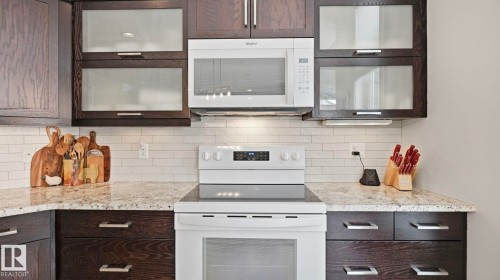 The kitchen features dark wood cabinetry, a white subway tile backsplash, granite countertops, and stainless steel hardware - 131 North Ridge Drive, St. Albert, AB - Indoor Photo Showing Kitchen
