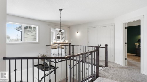 Upper landing featuring a staircase with black metal balusters and dark wood handrails, light gray carpet, and a window providing natural light - 131 North Ridge Drive, St. Albert, AB - Indoor Photo Showing Other Room