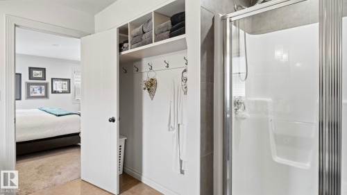 The property features an open closet with shelving and hooks, a standing shower with a glass door, and a carpeted room visible through the doorway - 131 North Ridge Drive, St. Albert, AB - Indoor Photo Showing Bathroom